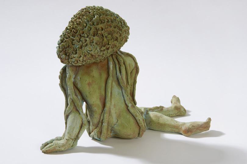 TOPIA, from the Latin topias meaning “ornamental garden”, is a nude figure leaning on one arm and sporting a topiary-like headdress. 
