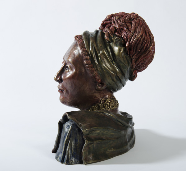 SHEBA, myhto-historical bust of a draped woman with headband and dreadlocks, head turned to the left. 